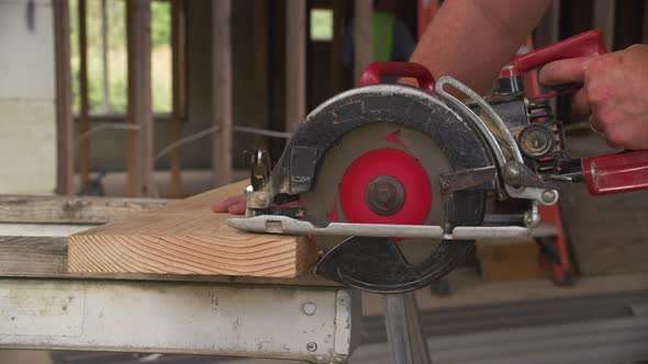 Closeup of construction worker cutting with circular saw
