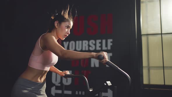 Sportswoman workout exercising by spinning on stationary bicycles cardiovascular machine for health. alt