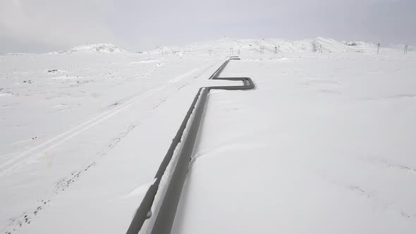 Aerial view of gas pipes through snowy frozen countryside in Iceland