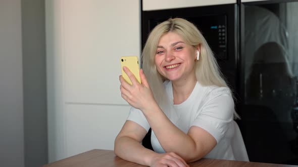 Young attractive woman looks into a smartphone and then into the camera