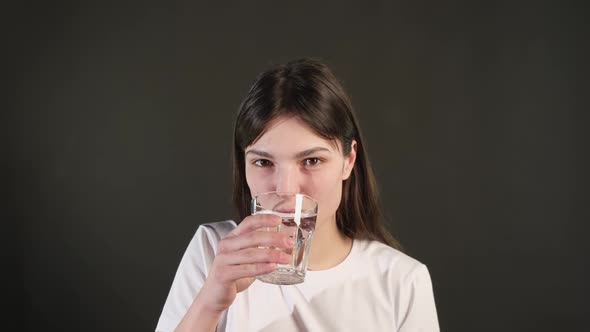 a young girl holds a glass and drinks fresh, clean, filtered mineral water.