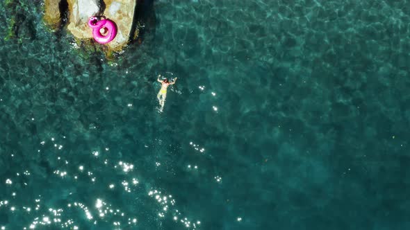 Aerial Drone Birds Eye View Shot of Woman in Yellow Swimsuit Swimming in the Sea with Clear and alt