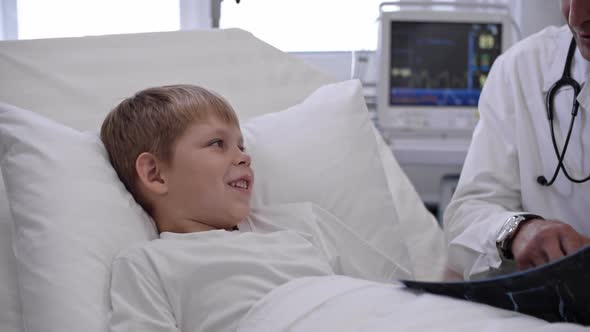 Doctor Speaking with Little Boy about X-Ray Results alt