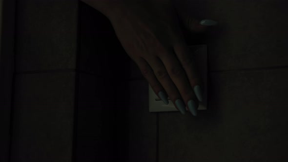 Electricity Young Woman Turns on Light Indoors with Switch on Wall Closeup alt