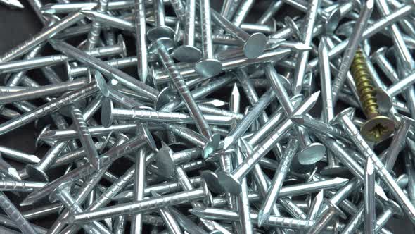 Metal Nails for Construction Work Spill Out Onto the Rotating Black Surface Hobnails are Spinning alt