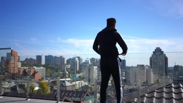 Wide Shot Confident Middle Eastern Sportsman Stretching Legs Standing at Glass Fence on Building alt