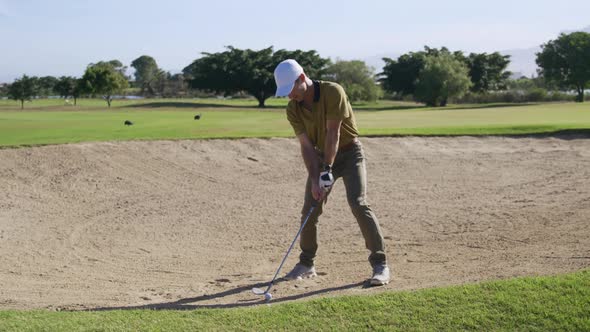 Golf player hitting the ball with his club alt