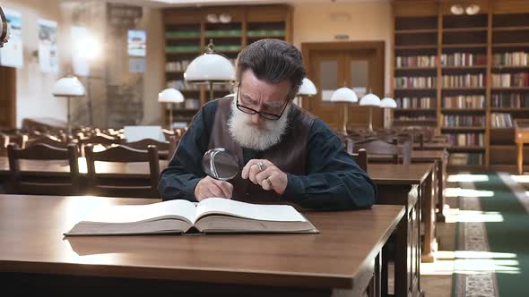 Old Man in Glasses which Recording Important Notes From the Book, Sitting in the Library alt
