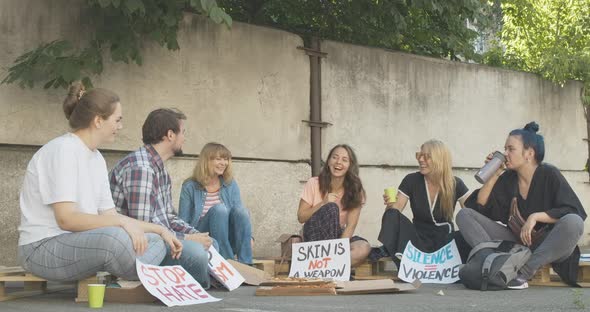 Wide Shot of Positive Demonstrators Resting After Protest with Pizza. Laughing Young Caucasian Men alt
