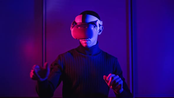 Young Man in VR Helmet Interacts with Virtual Reality Using His Hands alt