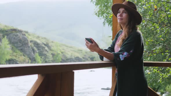 Attractive Brunette in a Hat and a White Shirt with Peas Talking on a Cell Phone, Taking a Selfie on alt