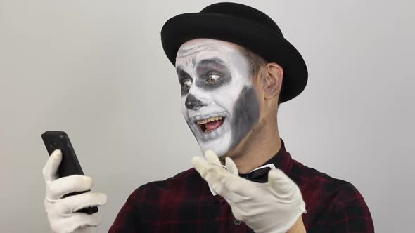 A Terrible Man in Clown Makeup and Video Chat. The Scary Clown Communicates with Friends Via Video alt