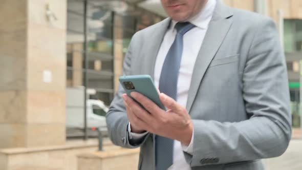 Close Up of Male Hands Using Smartphone while Walking on Street alt