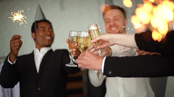 Close-up Team of Celebrating Success at Office Holding Bengal Lights, Clinking Glasses of Champagne alt