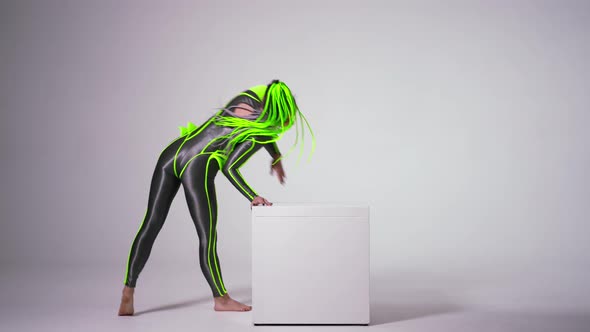 Wide Shot Portrait of Confident Beautiful Artist Rolling Over Cube at White Background Looking at alt
