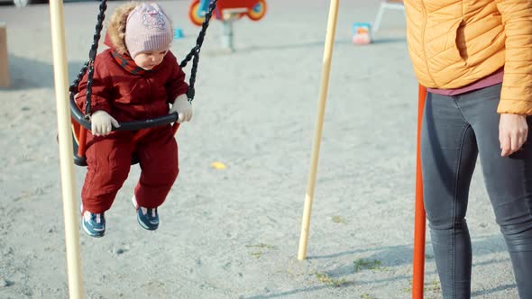 Cheerful Smiling Cute Little Girl Swinging In Park.Smiling Enjoying Happy Family Daughter Having Fun alt