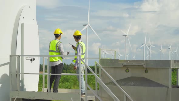 Teamwork of Asian windmill engineer group, worker working on site at wind turbines field or farm,