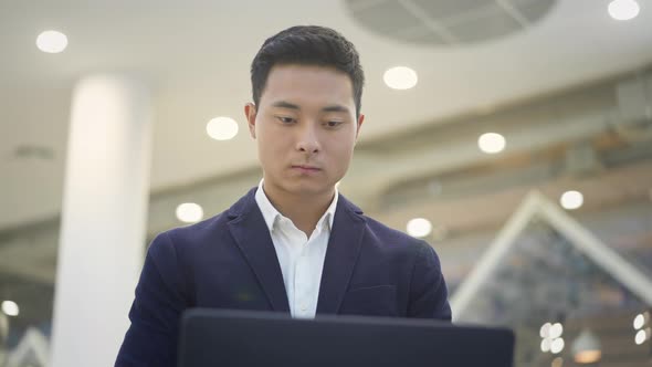 Close Up of Asian Male Businessman in Suit Working with Laptop on His Knees