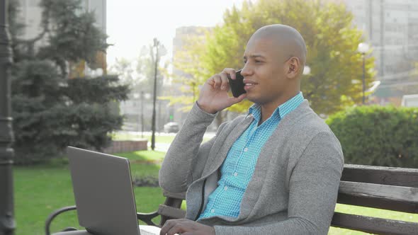 Handsome African American Businessman Using Smart Phone and Laptop Outdoors alt