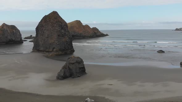 Aerial of rugged picturesque beach and small islands of rock off the Pacific Ocean in Oregon.  Sand, alt