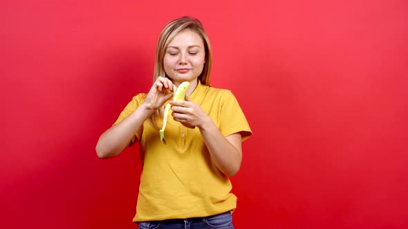 Attractive and Slightly Fat Young Woman on a Red Background. You Have a Banana in Your Hand. alt