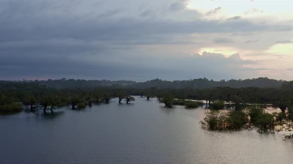 Nature background, flying over a lake in a tropical forest during sunset alt