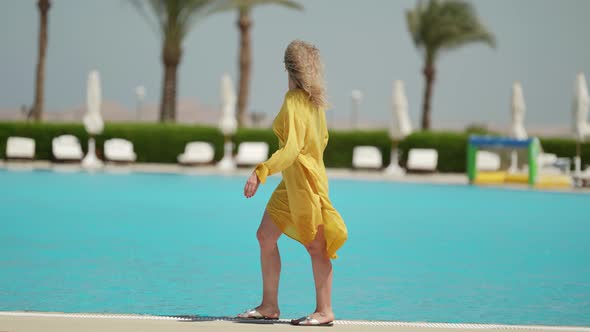 Rest in Luxury Hotel Woman is Strolling Along Open Pool in Sunny Day alt