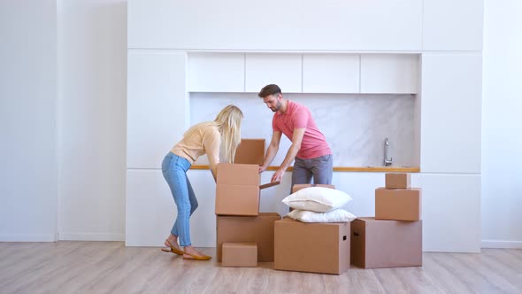 Young woman blonde with long loose hair and bearded husband open cardboard box alt