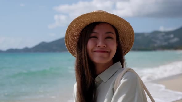 Slow motion of a beautiful young asian woman with hat on the beach