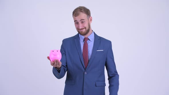 Happy Bearded Businessman Holding Piggy Bank and Giving Thumbs Up