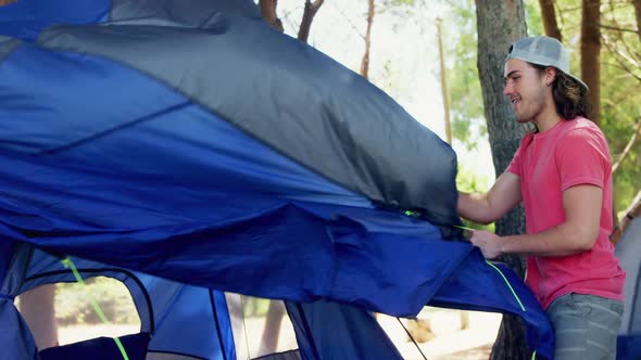 Happy man setting up tent in park 4k alt