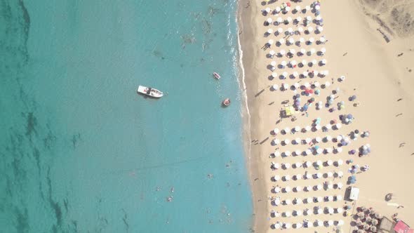 Top View of Sand Beach with Umbrellas Boat and Swimming People in Sea Bay Water alt