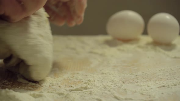 Male Hands Kneading Dough in Flour on the Table.