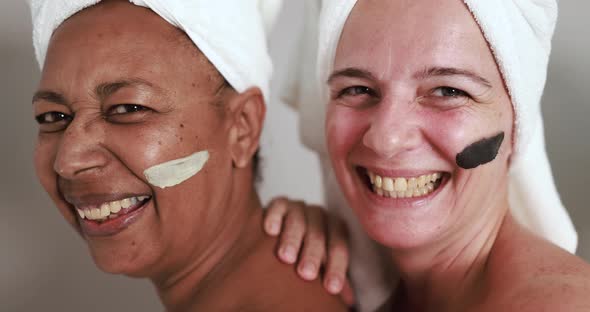 Mature caucasian and african women having fun doing beauty day together alt