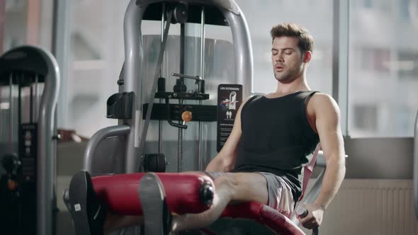 Strong Sportsman Doing Legs Exercise on Sport Simulator in Fitness Club alt