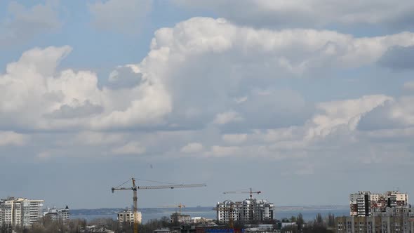 Construction Cranes Over Residential Buildings Rooftops and Cloudscape Time Lapse