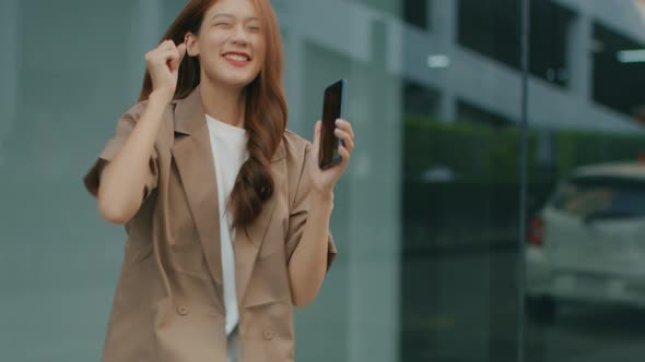 Excited Asian Asian Businesswoman having good news on phone