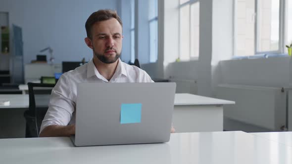 Serious Man Sits at the Grey Laptop alt