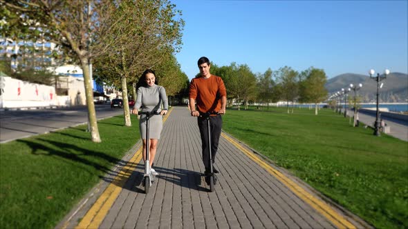 A Young Couple Is Riding a Electro Scooter at Urban Park