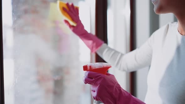 African pregnant woman wiping the window with a damp cloth alt