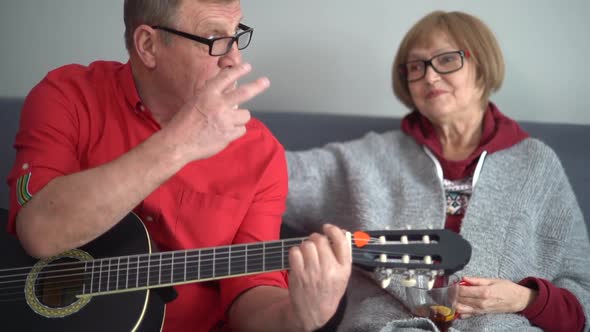 Portrait of an Elderly Couple Enjoying Playing the Guitar in Their Own Home