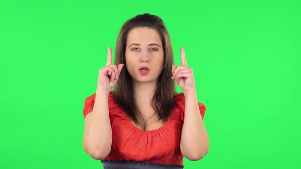 Portrait of Cute Girl Pointing Fingers Up for Something with Copy Space.. Green Screen alt