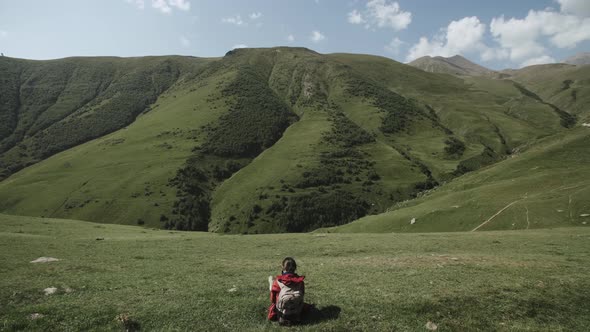 Female Traveler Sits on Hill Above the Mountain Gorge. Young Woman Highland Mountain Landscape alt