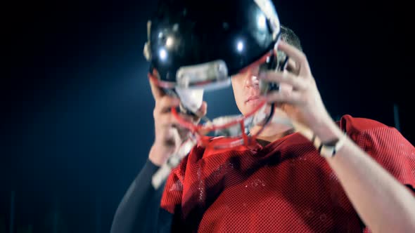Footballer Is Putting on His Helmet While Being in a American Football Arena alt