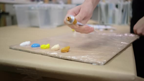 Painter Is Squeezing Dyes From Tubes in Work Studio Closeup alt