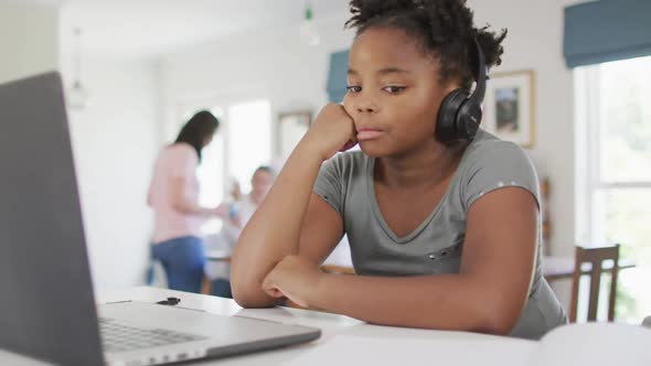 Happy african american girl using laptop for online lesson at home alt
