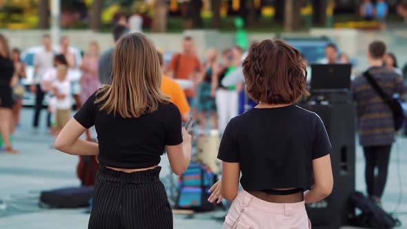 Teenage girls dancing on street during musical festival alt