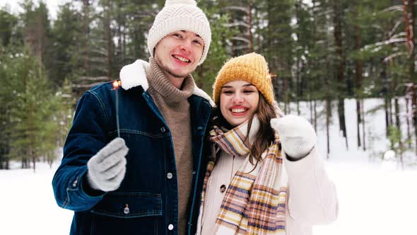 Happy Couple with Sparklers in Winter Forest