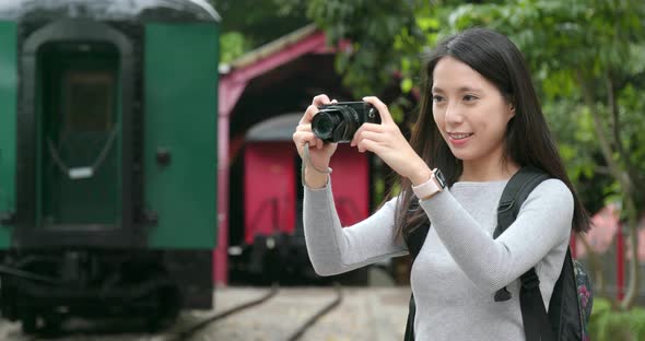 Woman traveling and taking photo in train station alt