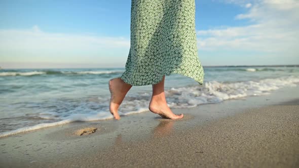 Legs of a Young Woman in Slow Motion Walking Barefoot on the Beach alt